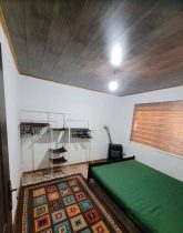 تخت خواب با روتختی سبز و فرش قهوه ای و پرده کرکره ای اتاق خواب خانه روستایی در رودسر