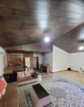 مبل راحتی و فرش طوسی رنگ و سقف چوبی خانه روستایی در رودسر