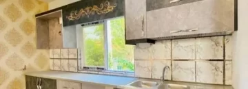 کابینت های طوسی مشکی و پنجره رو به محوطه سبز آشپزخانه ویلا در صومعه سرا